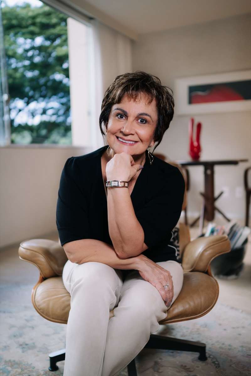 Dra. Regina Celi sentada em uma poltrona em seu consultório